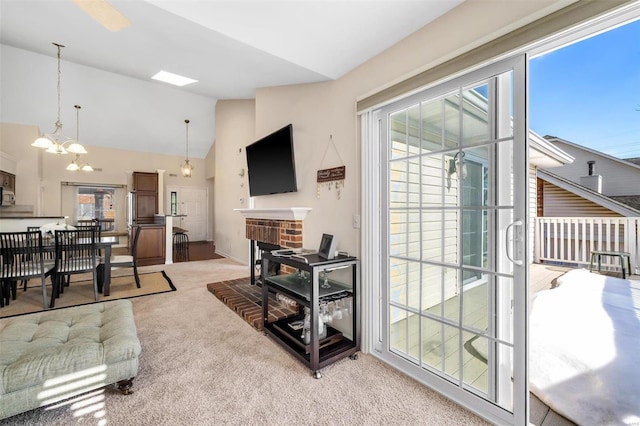 living room with vaulted ceiling, a fireplace, a chandelier, and carpet floors