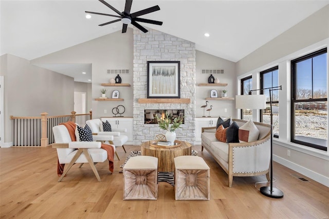 sitting room featuring ceiling fan, vaulted ceiling, a fireplace, and light hardwood / wood-style floors