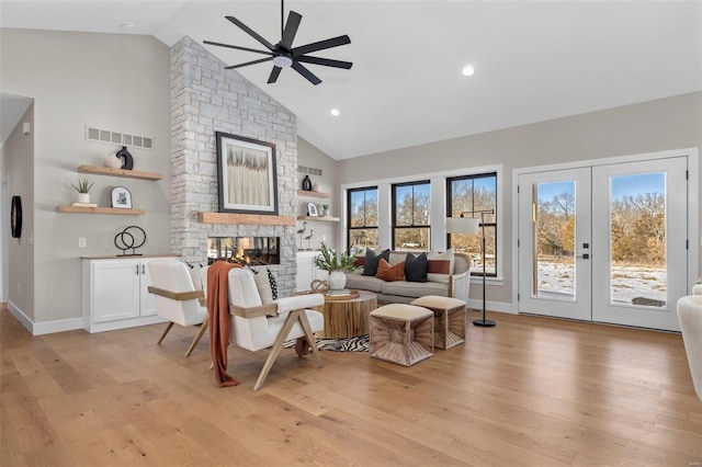 interior space with light wood-type flooring, ceiling fan, a fireplace, and french doors