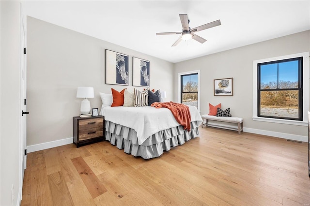 bedroom featuring ceiling fan, multiple windows, and light hardwood / wood-style flooring