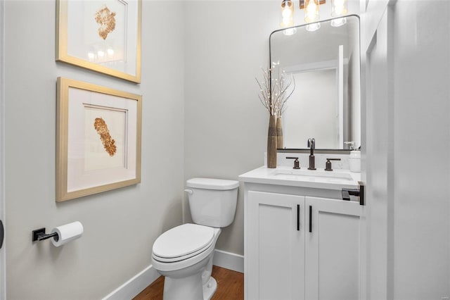 bathroom with toilet, vanity, and wood-type flooring