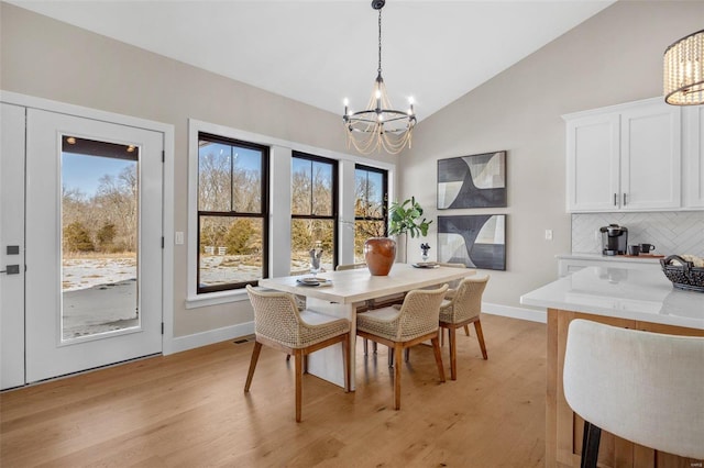 dining area with light hardwood / wood-style floors, lofted ceiling, and a notable chandelier