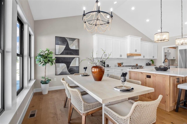 kitchen featuring pendant lighting, white cabinetry, a chandelier, and an island with sink