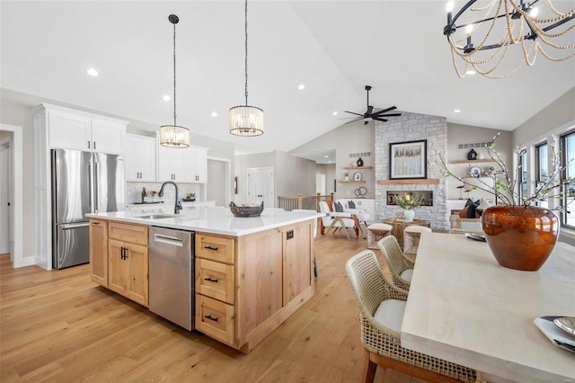 kitchen featuring light countertops, light wood finished floors, appliances with stainless steel finishes, a sink, and ceiling fan with notable chandelier
