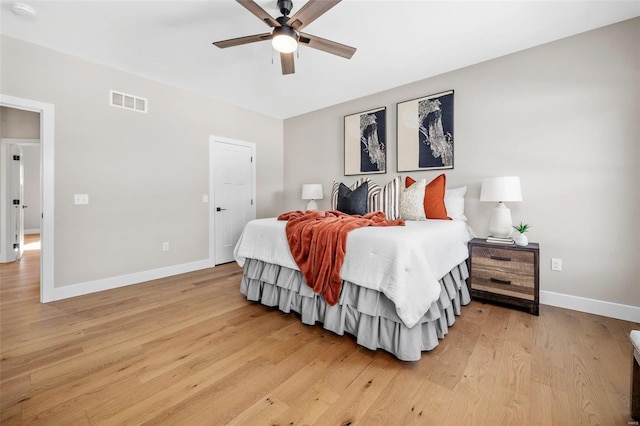 bedroom featuring baseboards, visible vents, ceiling fan, and light wood-style flooring