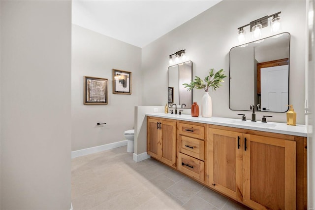 full bath with baseboards, toilet, double vanity, and a sink