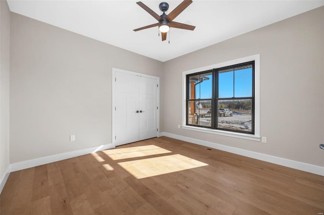 unfurnished bedroom with a ceiling fan, a closet, baseboards, and wood finished floors