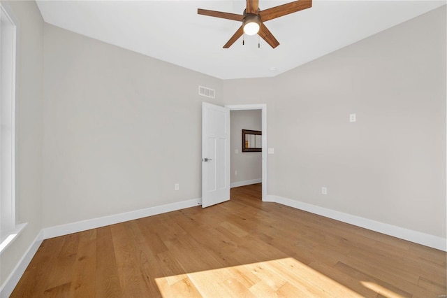 empty room featuring baseboards, light wood-style floors, ceiling fan, and visible vents