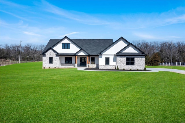 modern farmhouse featuring stone siding and a front yard