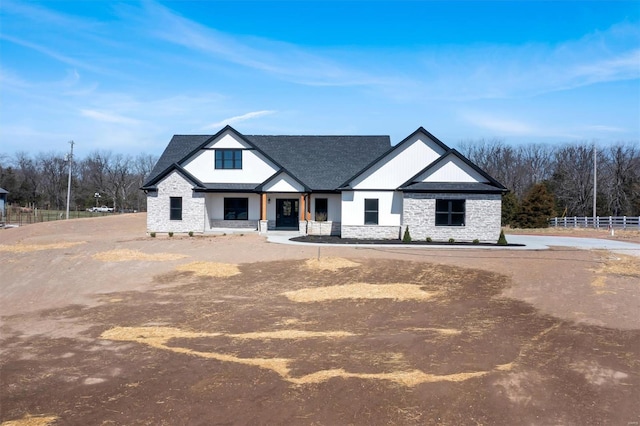 modern farmhouse style home featuring stone siding and fence