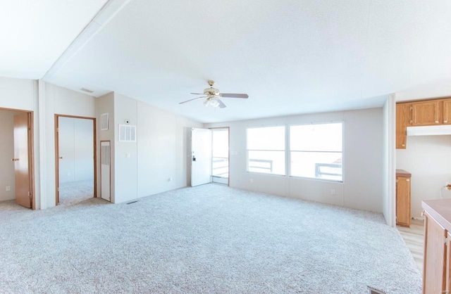 unfurnished living room featuring ceiling fan and light carpet