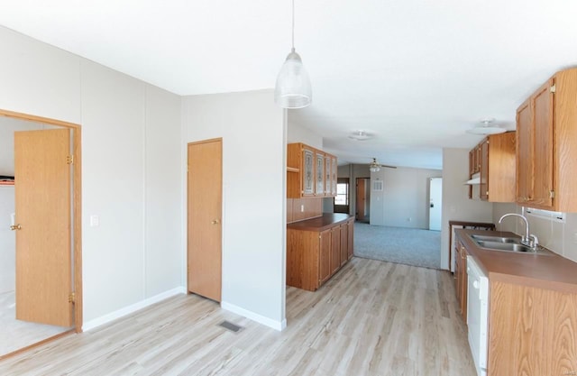 kitchen featuring ceiling fan, sink, white dishwasher, hanging light fixtures, and light wood-type flooring