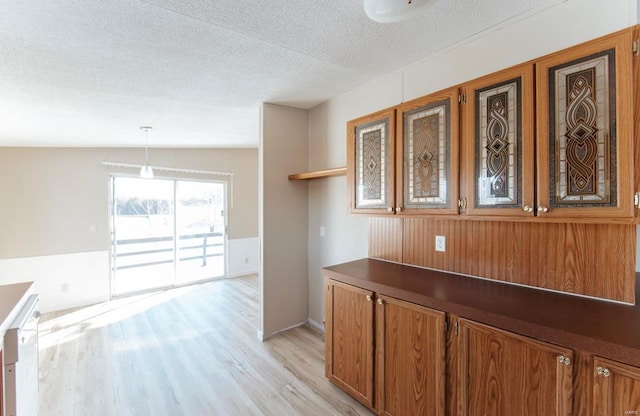 interior space with a textured ceiling, lofted ceiling, decorative light fixtures, white dishwasher, and light hardwood / wood-style flooring