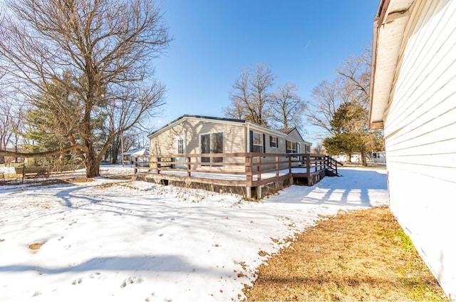 snow covered back of property featuring a deck