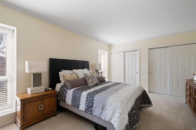 bedroom with ornamental molding, two closets, and light colored carpet