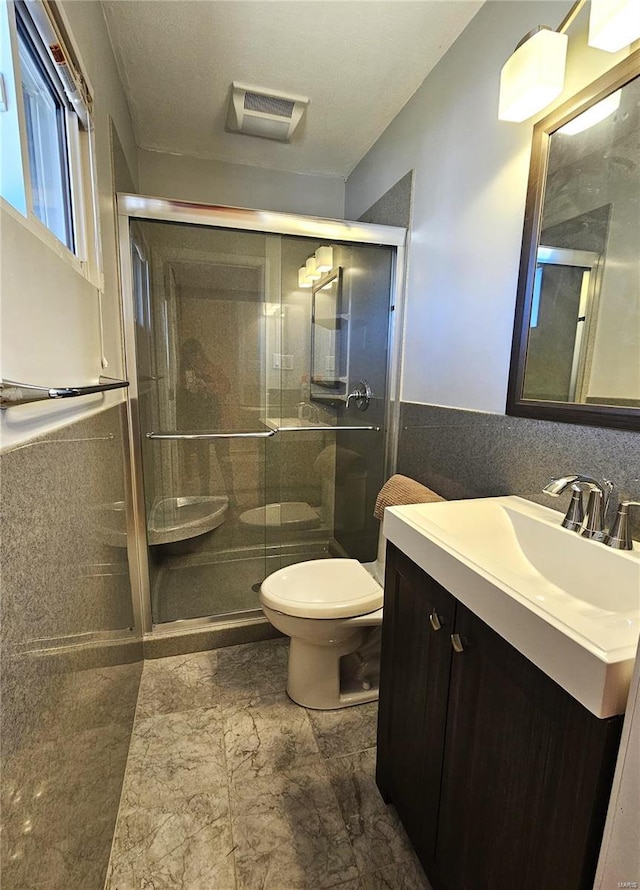 bathroom with vanity, a wainscoted wall, visible vents, a stall shower, and toilet