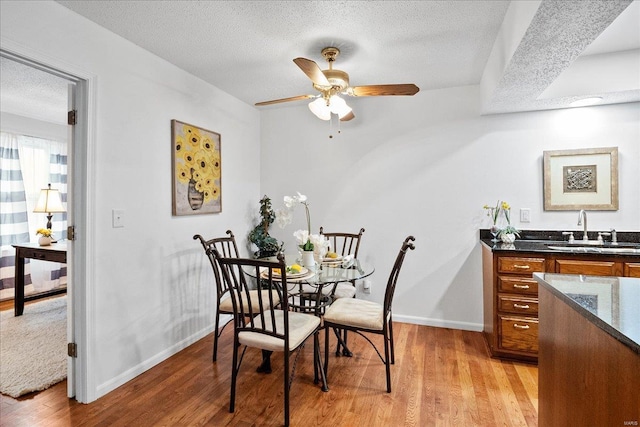 dining room with light wood-type flooring, sink, a textured ceiling, and ceiling fan