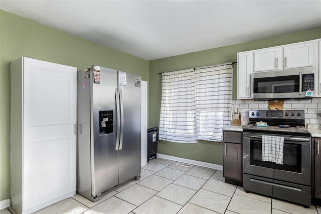 kitchen with light tile patterned flooring, tasteful backsplash, white cabinetry, and stainless steel appliances