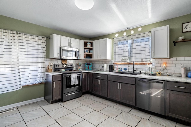 kitchen featuring a textured ceiling, appliances with stainless steel finishes, white cabinetry, tasteful backsplash, and sink