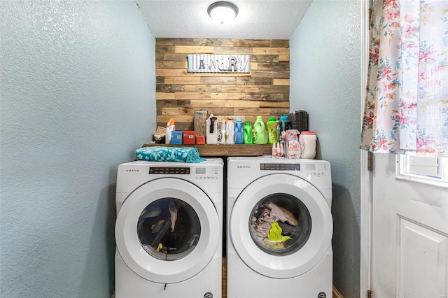 laundry area featuring separate washer and dryer, a textured ceiling, and wood walls