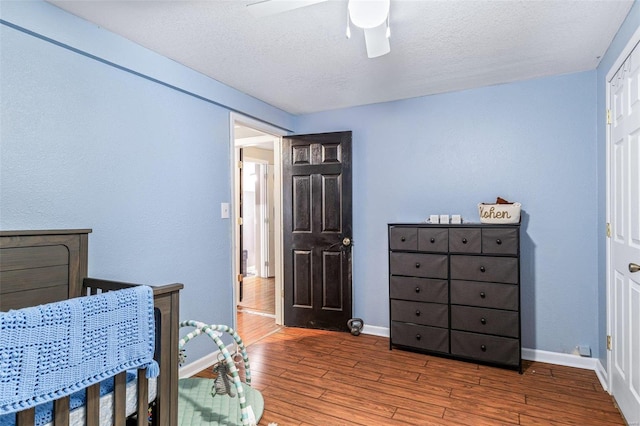 bedroom with ceiling fan, wood-type flooring, and a textured ceiling