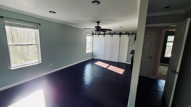 spare room featuring ceiling fan, dark hardwood / wood-style flooring, crown molding, and a barn door