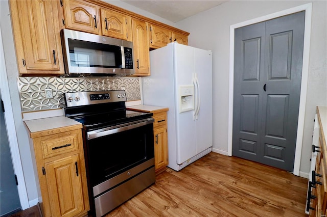 kitchen with light wood-type flooring, stainless steel appliances, and tasteful backsplash