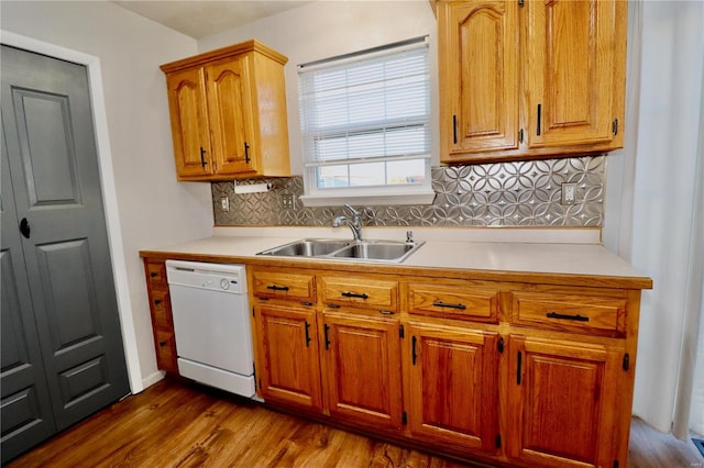 kitchen with backsplash, dishwasher, sink, and wood-type flooring