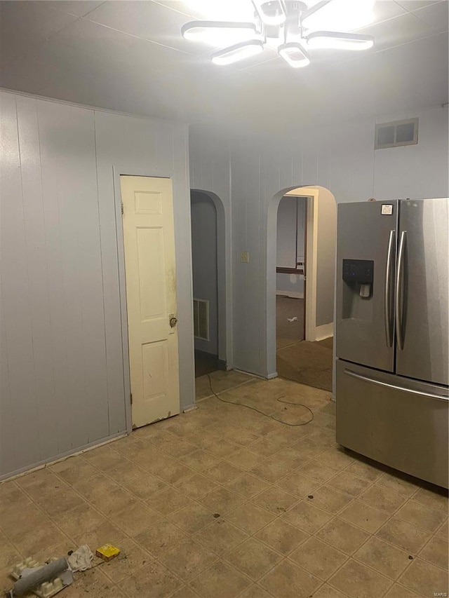 kitchen featuring wooden walls and stainless steel fridge with ice dispenser