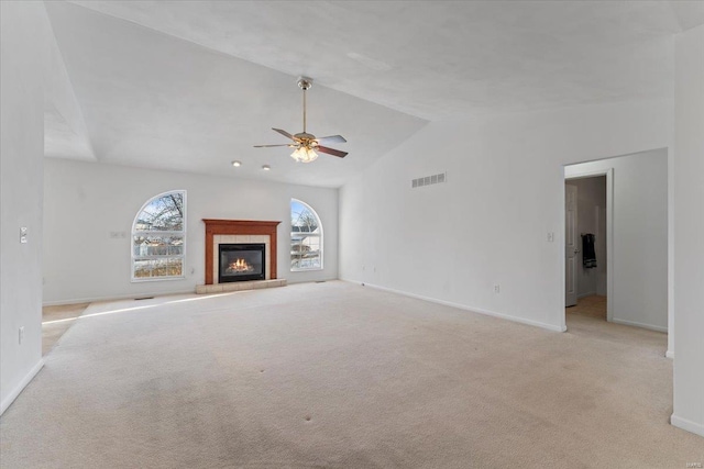 unfurnished living room featuring ceiling fan, high vaulted ceiling, light carpet, and a tiled fireplace