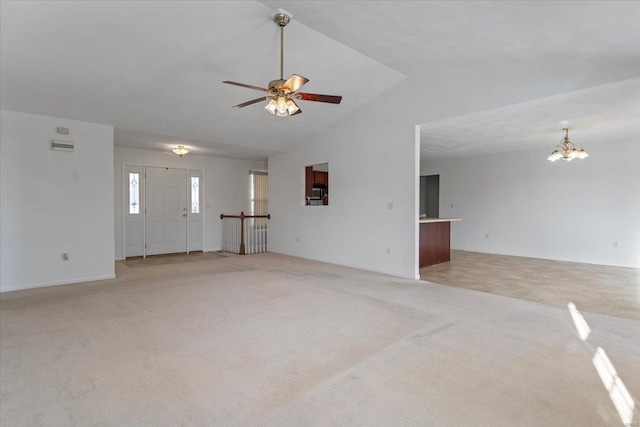 unfurnished living room with ceiling fan with notable chandelier, light carpet, and vaulted ceiling