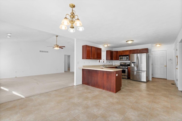 kitchen featuring ceiling fan with notable chandelier, pendant lighting, light carpet, stainless steel appliances, and kitchen peninsula