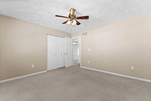 unfurnished bedroom with ceiling fan, light colored carpet, and a closet