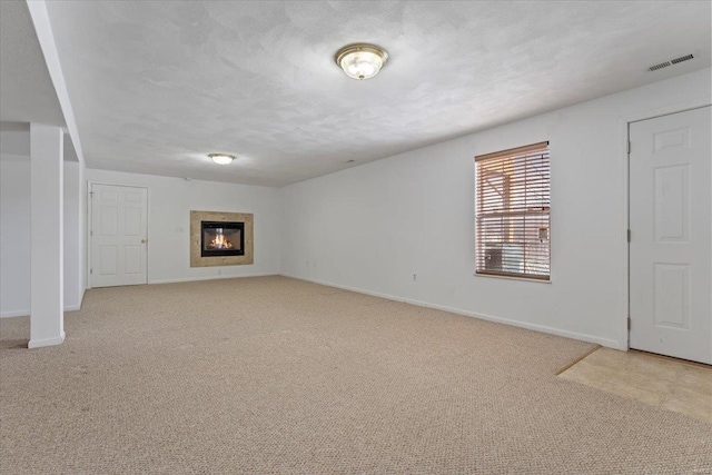 unfurnished living room featuring a textured ceiling and light colored carpet