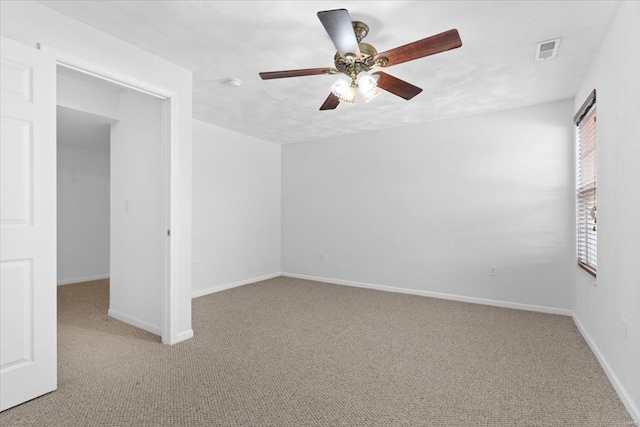 empty room with ceiling fan and light carpet