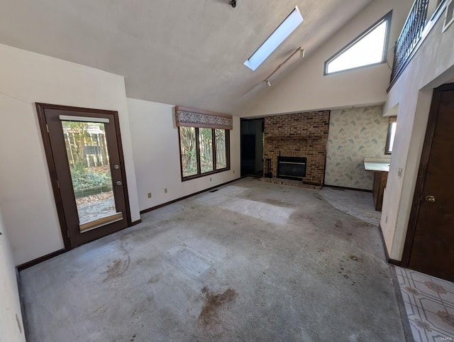 unfurnished living room with vaulted ceiling with skylight, plenty of natural light, and a brick fireplace