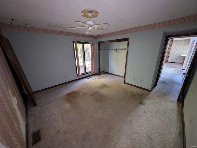 unfurnished bedroom with ceiling fan, crown molding, a closet, and light carpet