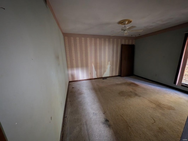 carpeted spare room with ceiling fan and ornamental molding