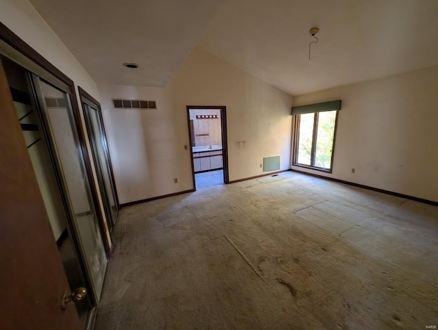 empty room featuring vaulted ceiling and light carpet