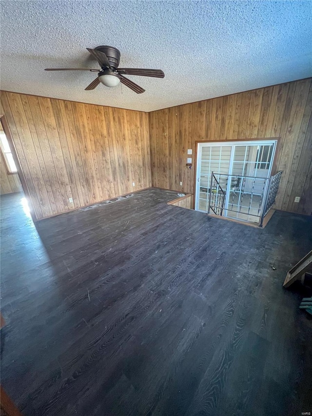 unfurnished room featuring wood walls, a textured ceiling, and dark hardwood / wood-style floors