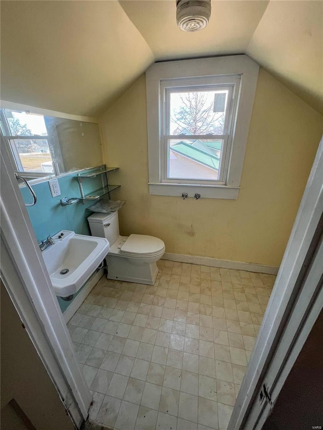 bathroom featuring sink, vaulted ceiling, plenty of natural light, and toilet