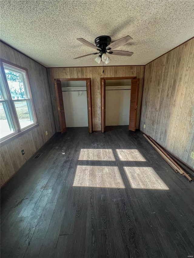 unfurnished bedroom featuring wood walls, ceiling fan, and dark hardwood / wood-style flooring