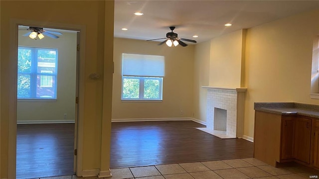 unfurnished living room featuring a fireplace, ceiling fan, and light tile patterned flooring