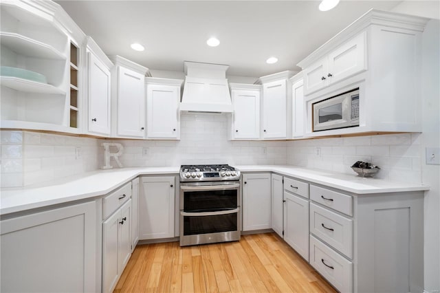 kitchen featuring premium range hood, white cabinetry, tasteful backsplash, light wood-type flooring, and stainless steel appliances