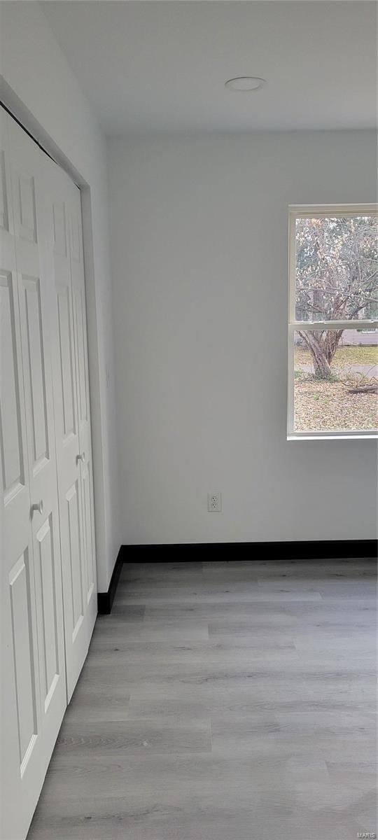 unfurnished bedroom with light wood-type flooring and a closet