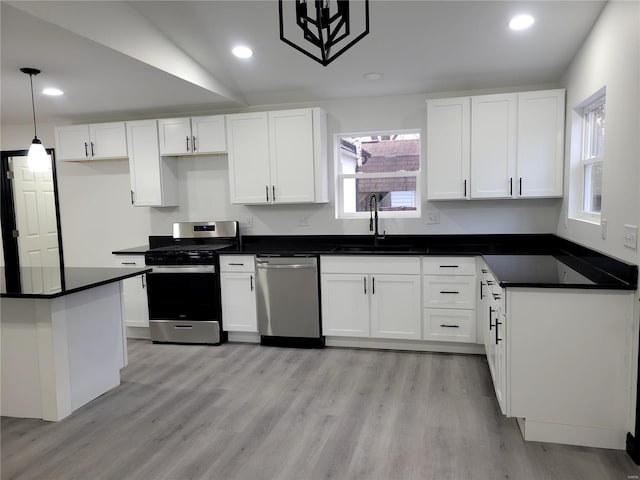 kitchen featuring white cabinetry, sink, hanging light fixtures, and stainless steel appliances