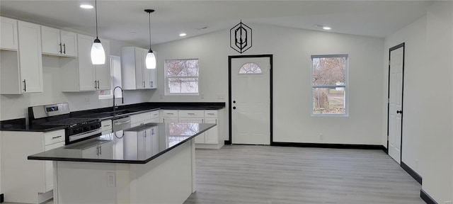 kitchen featuring pendant lighting, white cabinetry, stainless steel appliances, and vaulted ceiling