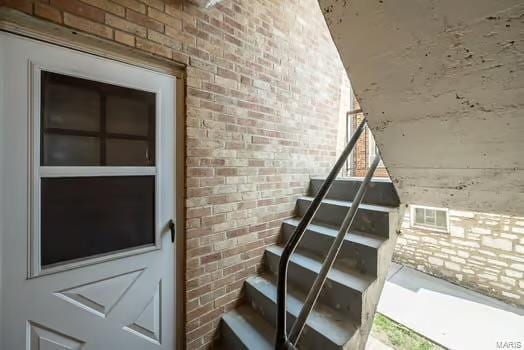 staircase featuring brick wall