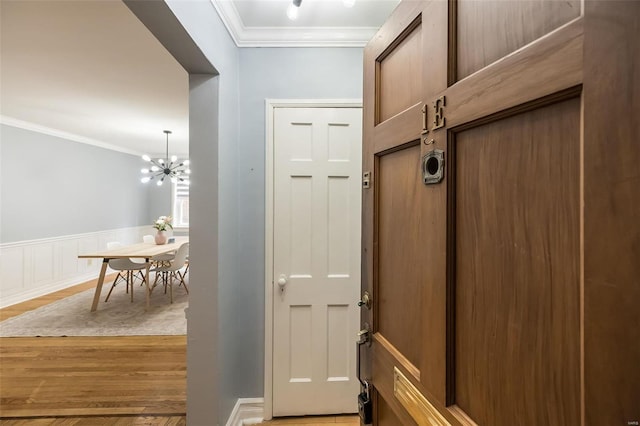 entryway featuring ornamental molding, an inviting chandelier, and light hardwood / wood-style floors