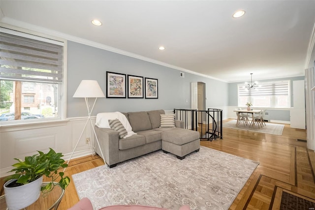 living room featuring crown molding, a notable chandelier, and light hardwood / wood-style flooring